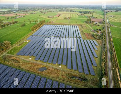 Grande ferme de panneaux solaires dans un paysage de campagne verdoyant, production d'énergie renouvelable, drone aérien large total Banque D'Images