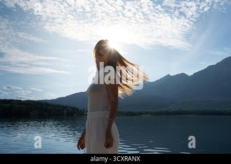 Femme en robe blanche profite du soleil au bord du lac. Pyramid Lake, Jasper, Alb Banque D'Images