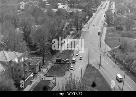 Une photo d'archives panoramique des années 1980 montre la vue depuis la jonction des rues Karla Marksa (aujourd'hui Tsentralna) et Yunykh Kommunarov (aujourd'hui Bankivska) à Sloviansk. La longue artère droite est animée par la circulation quotidienne, y compris un trolleybus articulé classique. Cette image illustre parfaitement l'ampleur du réseau de transports publics de la ville et le rythme quotidien d'un grand centre industriel. C'est un précieux document historique de l'environnement urbain dans un Donbass pacifique avant la guerre Banque D'Images