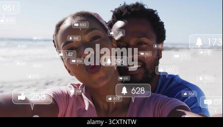Prise de couple selfie en haut rose, chemise bleue sur la plage ensoleillée, avec téléphone, notifications de médias sociaux Banque D'Images