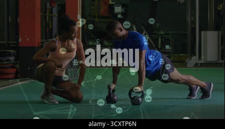 Formateur encadrant un client masculin faisant des pompes à l'aide de kettlebells dans le gymnase, espace de copie Banque D'Images