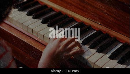 Fille chinoise avec manche rayée pressant des touches ivoire et noires dans le home studio, bande de feutre rouge Banque D'Images