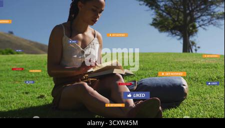 Femme lisant un livre à couverture rigide sur une colline sous un ciel clair, portant un haut rayé, un short à côté d'un tapis de denim Banque D'Images
