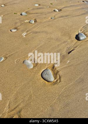 motifs créés par la mer. empreintes de pas dans le sable. plage de sable après marée haute. cailloux sur sable humide Banque D'Images