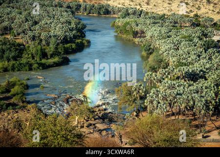 Un arc-en-ciel de lumière passant à travers le jet du canal principal des chutes d'Epupa depuis le point de vue Banque D'Images