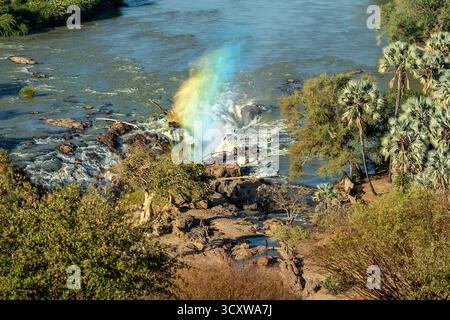 Un arc-en-ciel de lumière passant à travers le jet du canal principal des chutes d'Epupa depuis le point de vue Banque D'Images