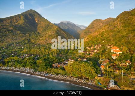 Vue aérienne de la plage noire avec les montagnes environnantes près d'Amed, Karangasem, Bali, Indonésie. Banque D'Images