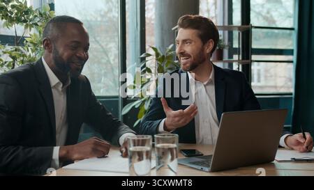 Deux hommes d'affaires riant de diversité équipe de bureau hommes d'affaires avec ordinateur portable heureux travailleurs collègues masculins satisfaits regarder l'ordinateur bons journaux de nouvelles Banque D'Images