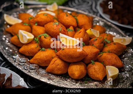 Turque traditionnelle et Arap icli kofte servis avec des quartiers de citron sur plateau argenté. Boulgour farci et doré, boulgour farci kibbeh. Plat populaire Banque D'Images