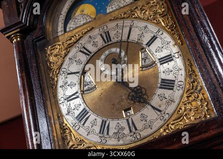 Une photo détaillée d'une horloge de grand-père vintage avec un centre en laiton, filigrane d'or complexe et un cadran à chiffres romains. Riche caisse en bois et moonp Banque D'Images