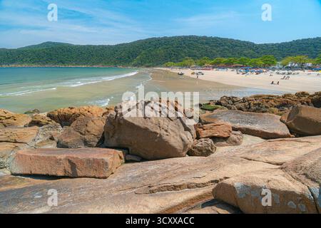 Plage de Guaiuba, Guaruja SP, Brésil. Journée ensoleillée sur la petite baie avec mer tranquille. Image des loisirs et du tourisme sur la côte de Sao Paulo. Collines couvertes Banque D'Images