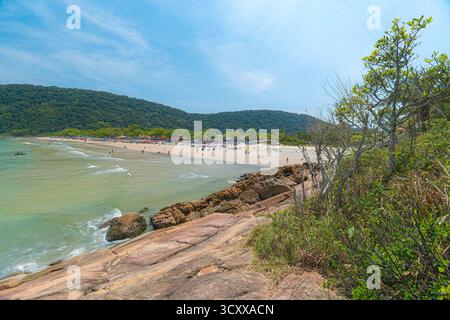 Plage de Guaiuba, Guaruja SP, Brésil. Journée ensoleillée sur la petite baie avec mer tranquille. Image des loisirs et du tourisme sur la côte de Sao Paulo. Collines couvertes Banque D'Images