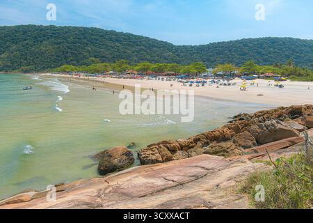 Plage de Guaiuba, Guaruja SP, Brésil. Journée ensoleillée sur la petite baie avec mer tranquille. Image des loisirs et du tourisme sur la côte de Sao Paulo. Collines couvertes Banque D'Images