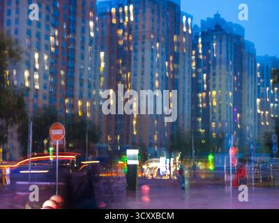 Les immeubles d'appartements modernes de Kiev flous avec d'innombrables fenêtres éclairées et les stries vibrantes des feux de voiture, représentant un u abstrait et énergique Banque D'Images