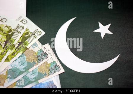 Pakistan roupies billets de banque sur fond de drapeau pakistanais. Les factures d'argent pakistanaises actuelles se trouvent sur la bannière en grand montant. Le concept d'économie et de bu Banque D'Images