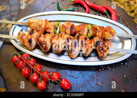 Gros plan de brochettes de poulet grillé scintillantes avec marinade, exposées dans un plateau en acier inoxydable, présentant une cuisine de barbecue appétissante. Photo de haute qualité Banque D'Images