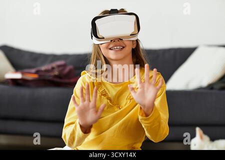 Un enfant gen alpha éprouve la joie de la réalité virtuelle tout en portant des lunettes de protection, entièrement immergé dans le temps de jeu. Banque D'Images