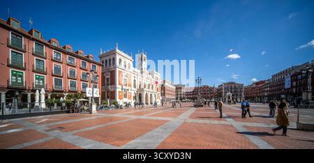 La Plaza Mayor de Valladolid est baignée par la lumière du jour d'automne, mettant en valeur les façades rouges et la vie animée sous un ciel bleu clair par une journée fraîche. Banque D'Images