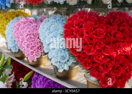 Arrangements floraux artificiels en forme de coeur à vendre à un étal de marché de cimetière. Banque D'Images