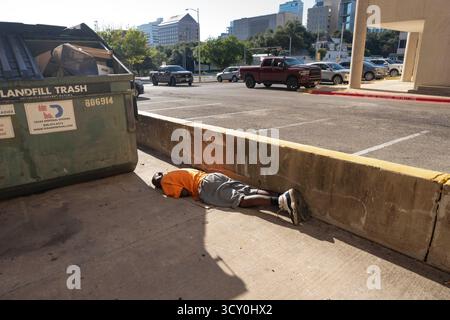 Un sans-abri semble dormir tard le matin dans une ruelle à une courte distance du manoir du gouverneur du Texas en arrière-plan le 11 octobre 2025. Les dirigeants d'Austin continuent d'essayer de nouvelles solutions pour aider sa population de sans-abri qui luttent quotidiennement pour trouver un abri, de la nourriture et des vêtements dans le centre urbain d'Austin. Banque D'Images