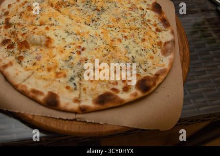 Pizza aux quatre fromages fraîchement cuite maison avec croûte croustillante et herbes aromatiques servie sur une planche de bois. Parfait pour le dîner ou concept de cuisine italienne. Banque D'Images