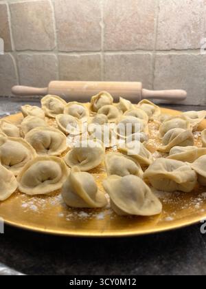 Boulettes maison non cuites sur la plaque dorée dans la cuisine et un rouleau à pâtisserie. Banque D'Images