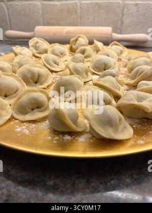 Boulettes maison non cuites sur la plaque dorée dans la cuisine et un rouleau à pâtisserie. Banque D'Images