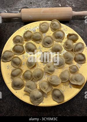 Boulettes maison non cuites sur la plaque dorée dans la cuisine et un rouleau à pâtisserie. Banque D'Images