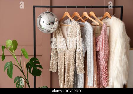 Rack avec vêtements suspendus et boule disco sur fond brun, gros plan Banque D'Images