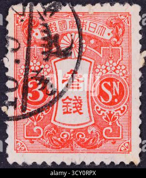 Un timbre-poste rouge et blanc présente des motifs complexes et du texte à la fois en japonais et ce qui semble être des lettres anglaises. Un grand nombre '3' est promi Banque D'Images