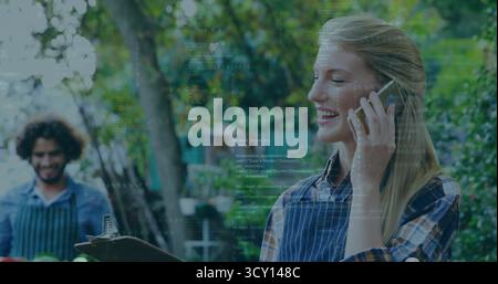 Tenant smartphone et vérifiant presse-papiers femme portant tablier au marché, avec caisses, espace de copie Banque D'Images