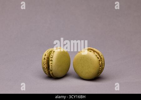 Paire de macarons vert et rose placés ensemble sur fond gris. Photographie de dessert simple et colorée pour la boulangerie ou le design. Banque D'Images
