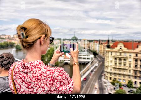 Tourist prend des photos surplombant Prague, République tchèque, avec vue sur les toits rouges, la rivière Vltava et l'architecture historique Banque D'Images
