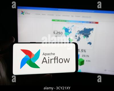 Dans cette illustration photo, une personne tient un smartphone avec le logo de la plate-forme de gestion de flux de travail Apache Airflow sur l'écran en face du site Web. Banque D'Images