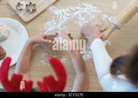 Fabrication de biscuits de Noël. Une mère et un enfant utilisant des emporte-pièces pour des friandises festives. Banque D'Images