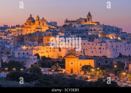 Une vue en soirée sur Ostuni, Pouilles, Italie, avec les maisons blanchies à la chaux de la « ville blanche » qui brillent dans des tons dorés chauds après le coucher du soleil. Le skyl historique Banque D'Images