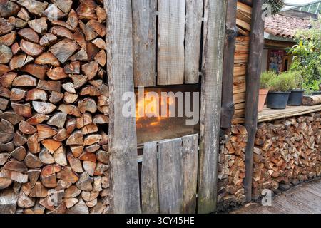 Vue latérale d'une pile empilée de bois de chauffage fendu et d'un fumoir Banque D'Images