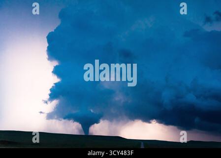 Les nuages sombres tourbillonnent avec une tornade éclairée par des éclairs lumineux, capturant les conditions météorologiques extrêmes, le ciel dramatique, l'énergie brute, la tempête nocturne Banque D'Images
