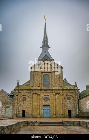 L'abbaye historique du Mont Saint-Michel se dresse majestueusement sous un ciel nuageux, mettant en valeur sa façade en pierre complexe et sa flèche imposante surmontée d'un coup de pouce Banque D'Images