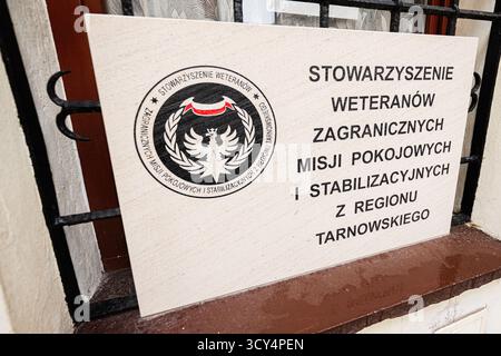 Tarnow, Pologne - 10 octobre 2025 : une plaque de pierre avec un emblème circulaire et une grande inscription polonaise montée à côté d'une fenêtre. Stowarzyszenie Weteranó Banque D'Images