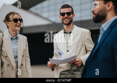 Des professionnels souriants appréciant une réunion d'affaires en plein air portant des lunettes de soleil élégantes. Banque D'Images