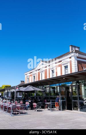 Vue des terrasses de cafés devant la gare de vannes dans le Morbihan en Bretagne en France le 24 juillet 2022. Les gens sont assis à des tables sous des parasols, Banque D'Images