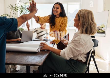 Architectes professionnels dans un espace de travail créatif célébrant le succès et le travail d’équipe dans leur projet. Banque D'Images