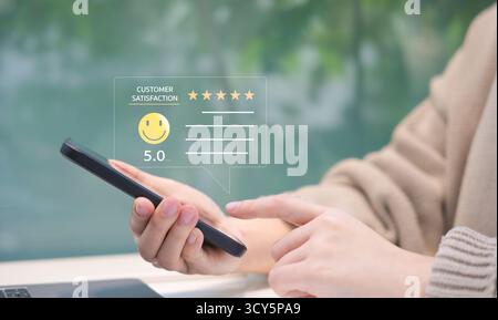 Concept d'enquête de satisfaction des clients. Personne donnant une note de satisfaction client cinq étoiles sur un téléphone intelligent, ce qui implique un excellent service Banque D'Images