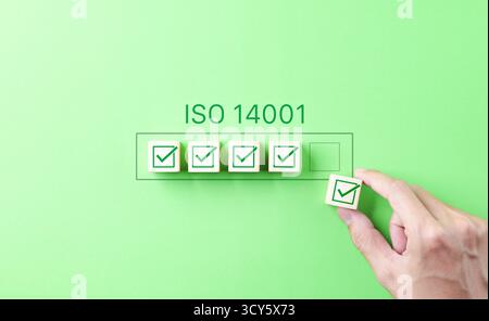 Concept de certification de gestion environnementale ISO 14001. La main place une coche sous le label ISO 14001, symbolisant le contrôle de la qualité, Banque D'Images