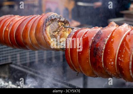 Porc rôti filé sur une brochette sur feu ouvert, viande juteuse avec croûte dorée croustillante, cuisson en plein air Banque D'Images