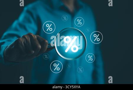 Concept de taux d'intérêt et de dividende. Homme d'affaires tient une loupe avec des symboles de pourcentage virtuel qui l'entourent, représentant le taux d'intérêt Banque D'Images
