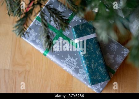 Les boîtes avec des cadeaux de Noël enveloppés dans du papier coloré et attachés avec du ruban d'emballage reposent sur le sol sous le sapin de Noël. Banque D'Images