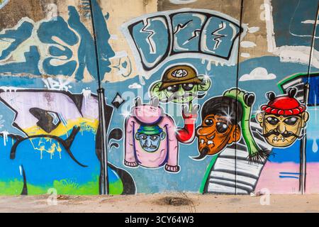 Une murale de Street art vibrante et fantaisiste mettant en vedette des personnages colorés de dessins animés avec des traits exagérés peints sur un mur urbain altéré Banque D'Images