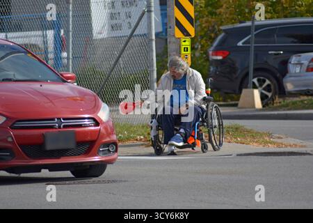 Un homme âgé sans-abri et handicapé est assis à un feu de circulation panguant pour de l'argent. Il tend son chapeau pour avoir passé des voitures dans lesquelles, espérons-le, déposer de l'argent. L'itinérance est devenue un grave problème dans le monde occidental. Au Canada, près de 240 000 personnes étaient sans-abri en 2024. Les taux ont presque doublé chaque année depuis 2019. Banque D'Images